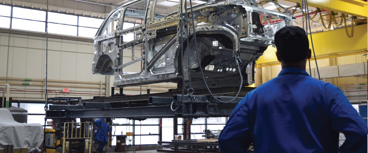 Engineer supervising the assembly of a car chassis in an automotive manufacturing plant