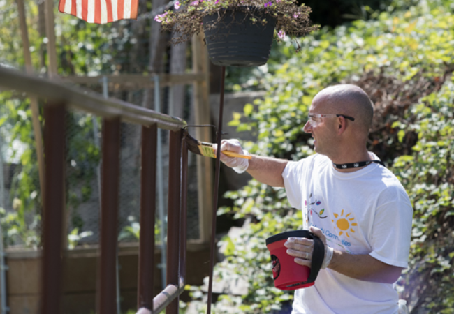 man painting railing brown 