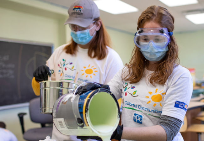 two women pouring light green paint 