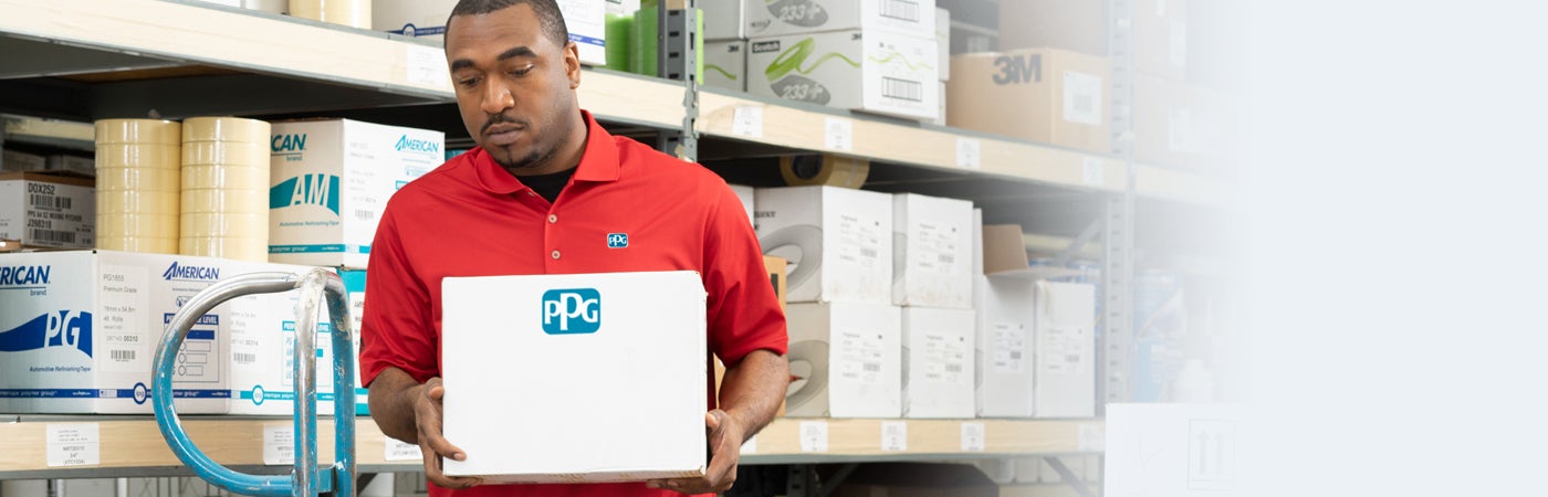 PPG employee carrying box in warehouse