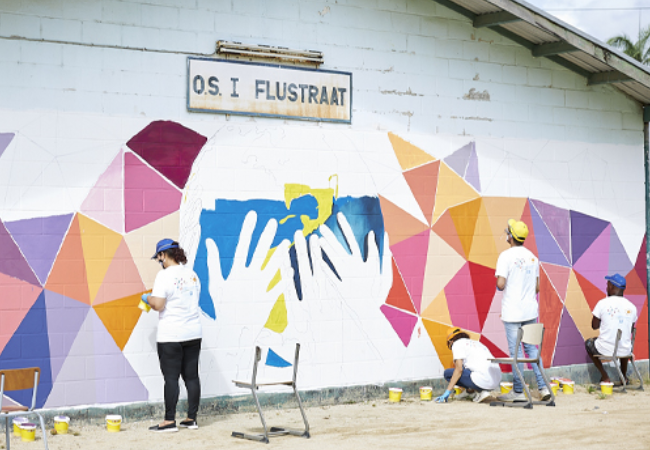 volunteers painting mural on side of building 