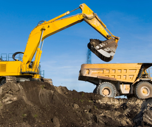 Yellow digger moving dirt into a yellow truck