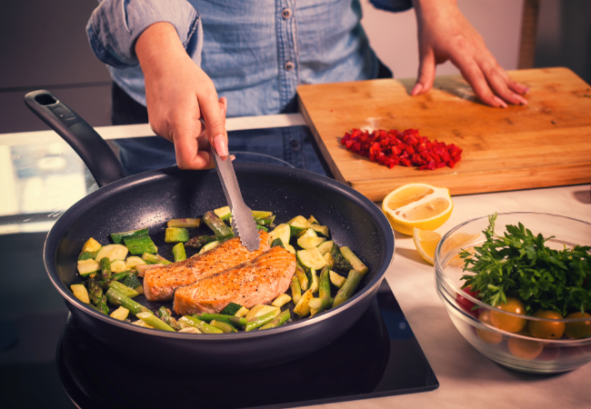 Female cooking dish with vegetables in a frying pan