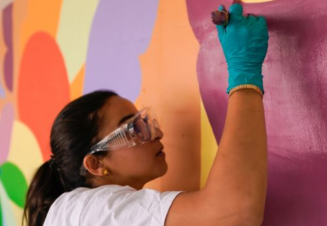 girl painting wall mural in Saultain, France 