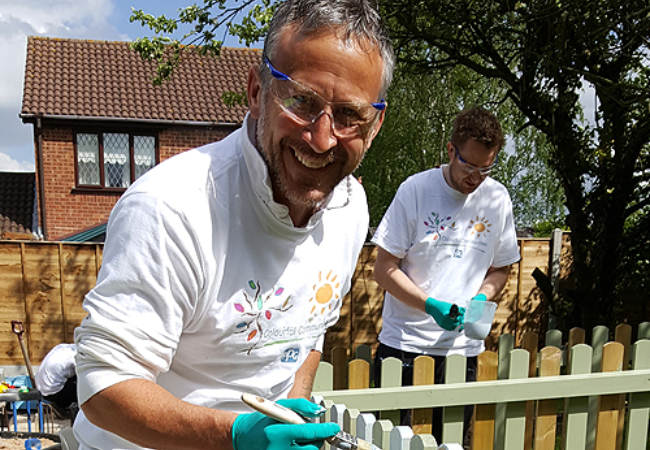 guy painting fence white in Suffolk, UK 