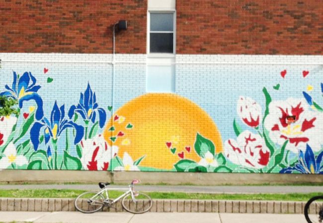 Exterior painted mural of sunshine and flowers