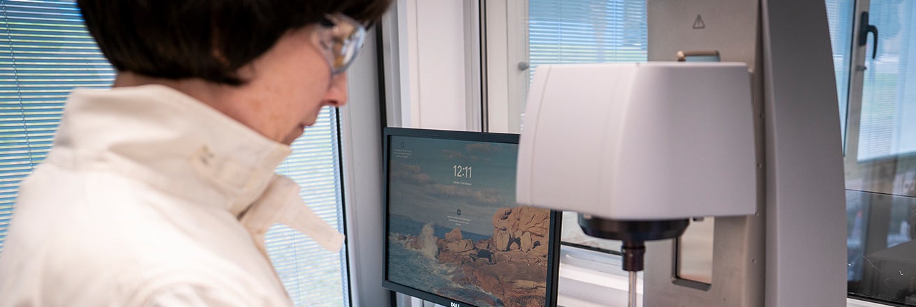 Female PPG worker wearing PPE next to computer and equipment