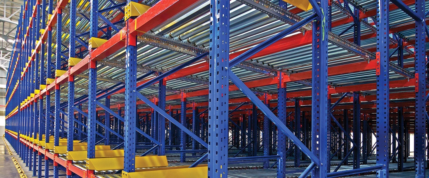 Long rows of blue and red steel racks in an industrial warehouse for organized storage, with yellow beam pallets excluding any visible inventory.