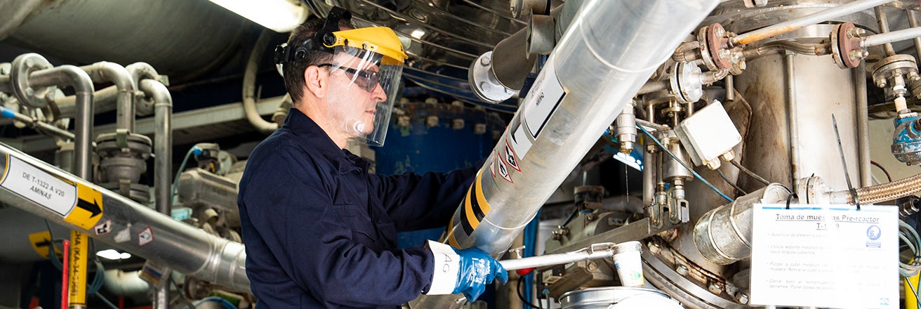 PPG employee wearing full PPE and following health and safety legislation surrounded by pipework