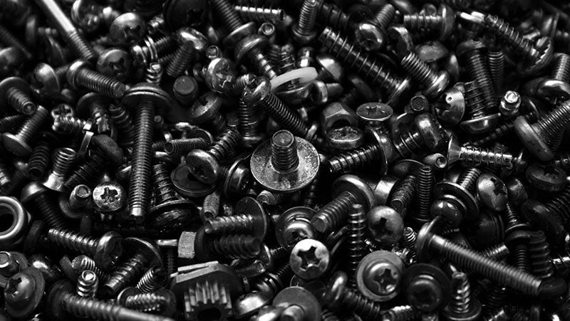 Close-up view of a variety of screws, bolts, and fasteners in black and white, showcasing different sizes and types