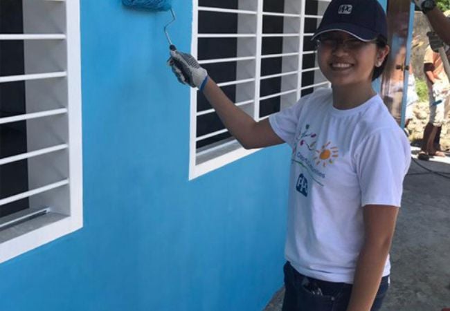 woman painting blue exterior wall