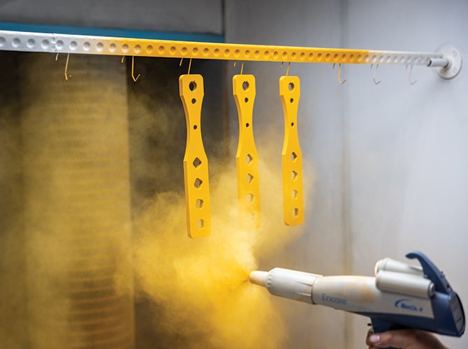 Spraying PPG sustainable yellow coating onto parts in a spray booth