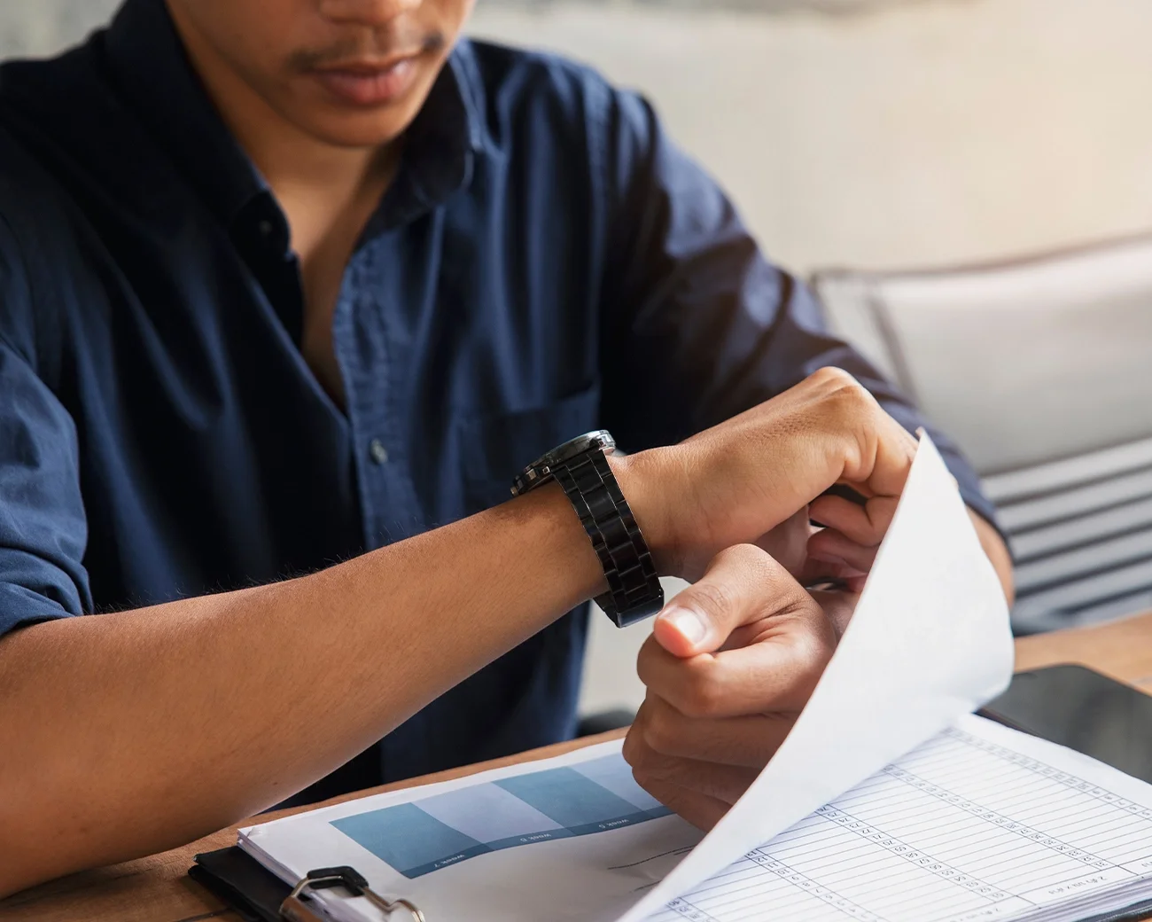 Man aan tafel kijkt op zijn horloge
