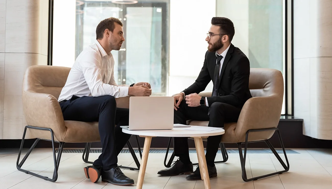 Twee mannen in gesprek naast een laptop