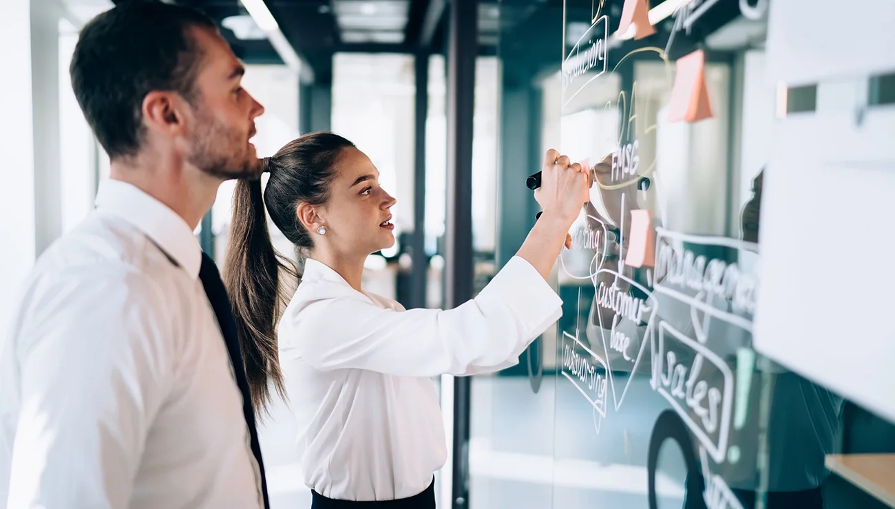 Twee collega’s schrijven notities op glazen raam