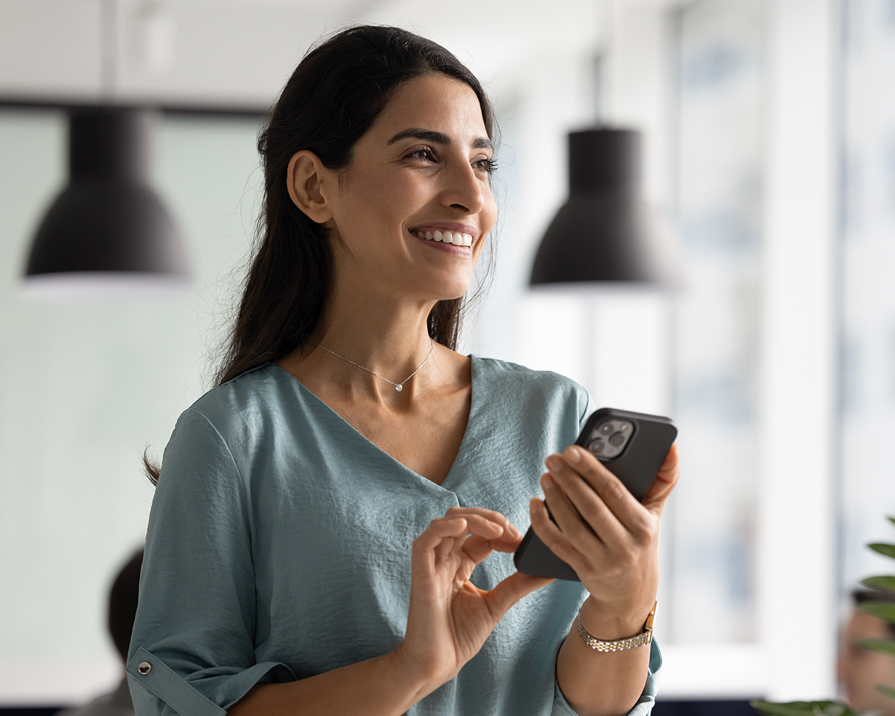 Vrouw kijkt lachend met telefoon in haar hand