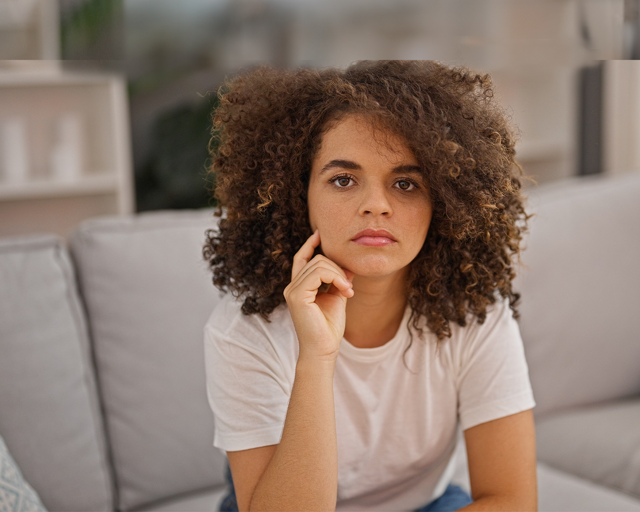 Vrouw met krullen zittend op de bank met geïrriteerde uitdrukking