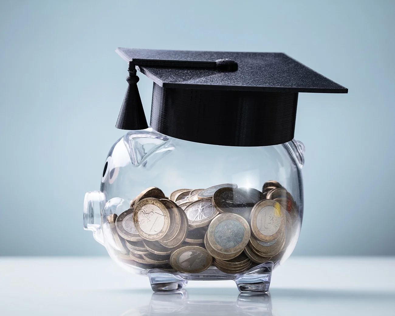 Glazen spaarpot vol euro's met collegehoed op