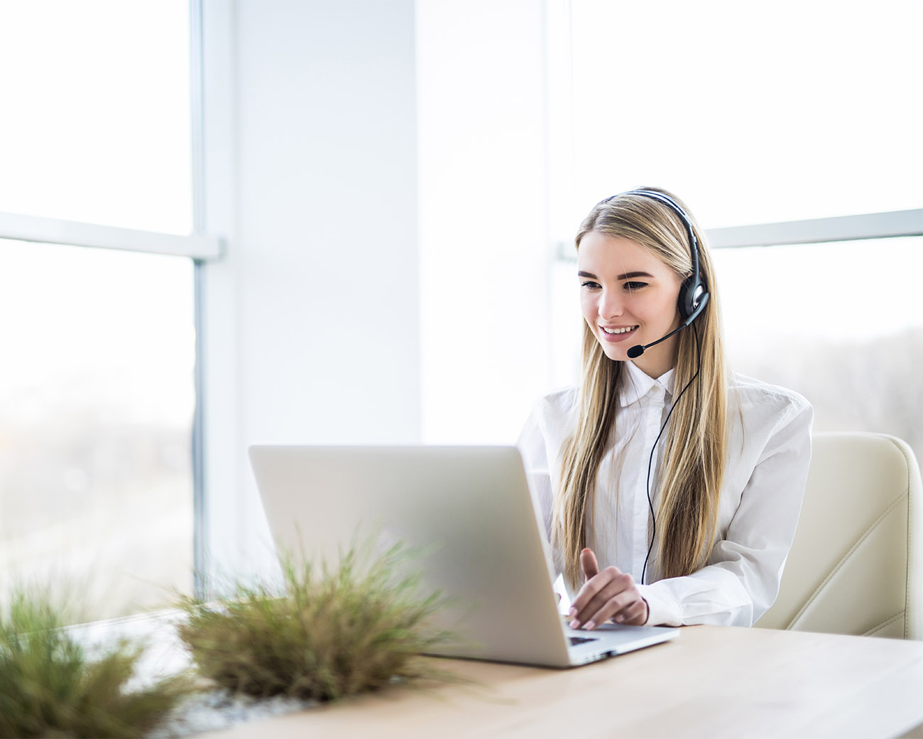 Vrouw met headset die werkt achter haar laptop