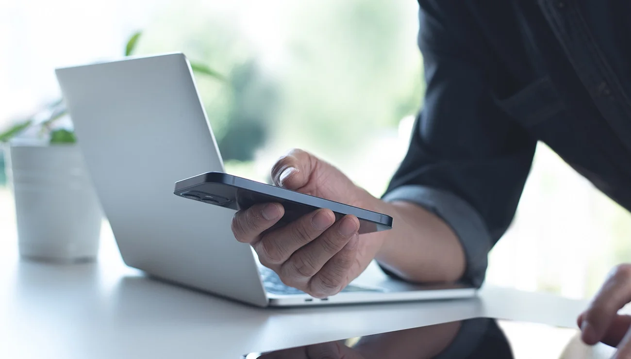 Man op zijn telefoon naast zijn laptop