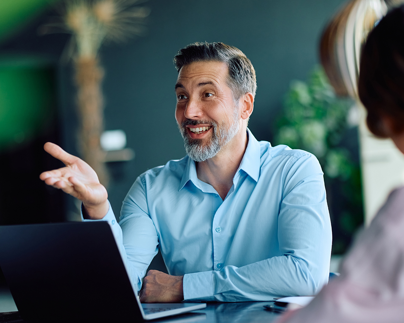 Man achter laptop maakt lachend gebaren