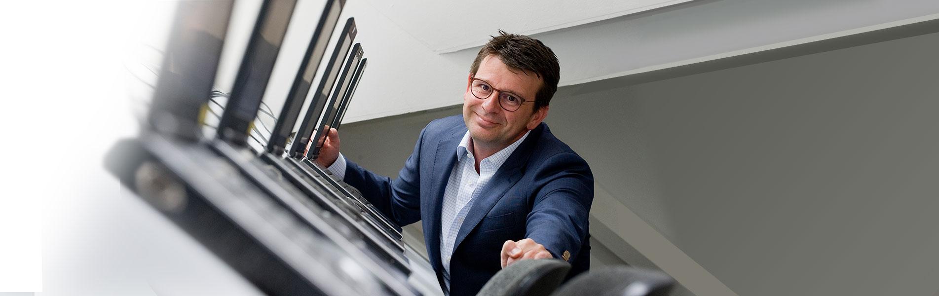 Docent Jan-Willem Stad staat achter een rij laptops