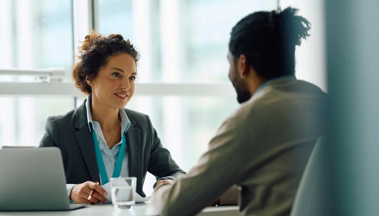 Twee mensen zitten tegenover elkaar aan een tafel en voeren een gesprek