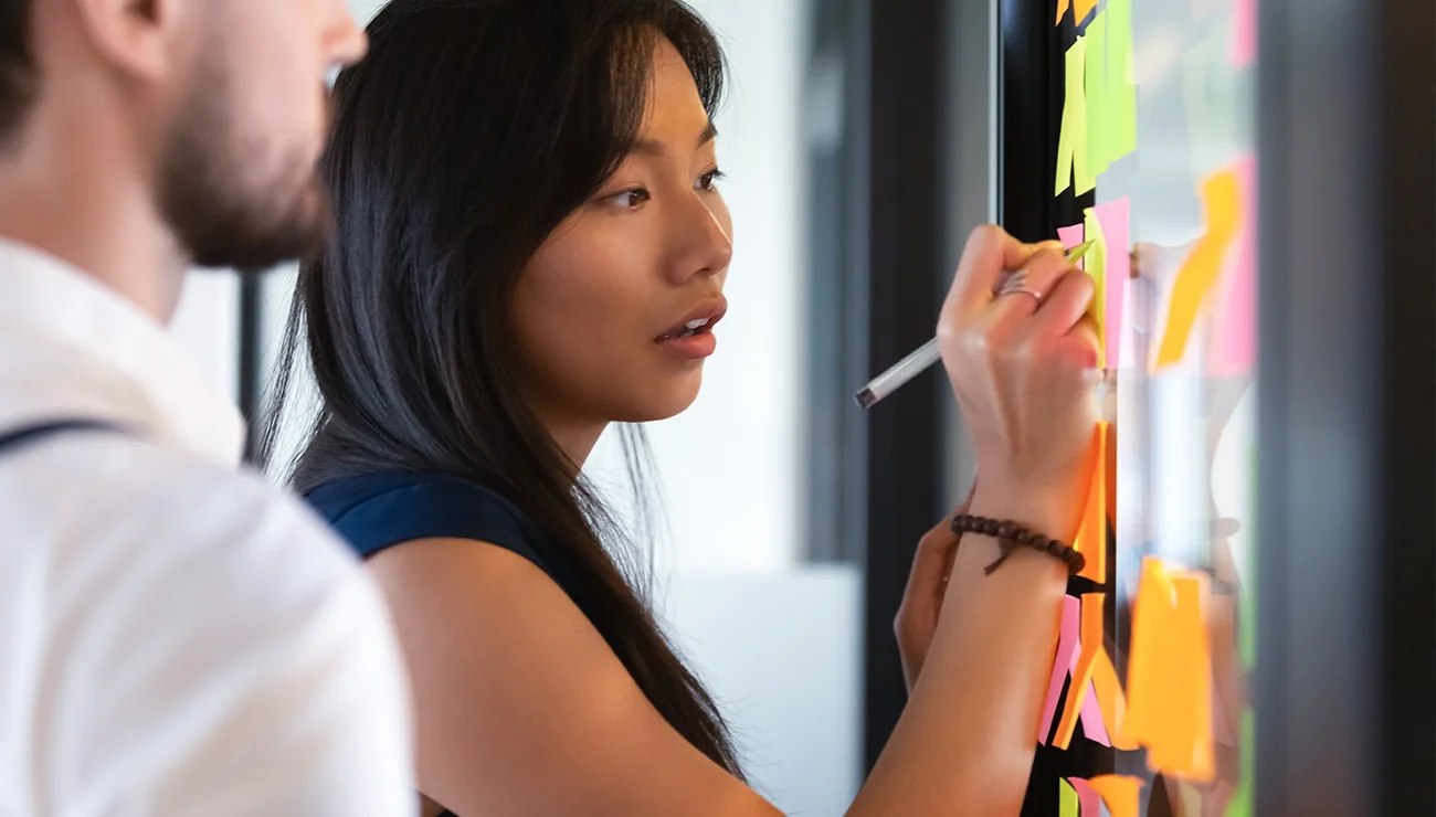 Vrouw schrijft op post-it op raam