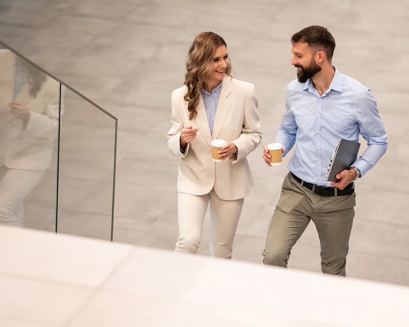 Twee professionals lopen trap op met koffie in hun hand