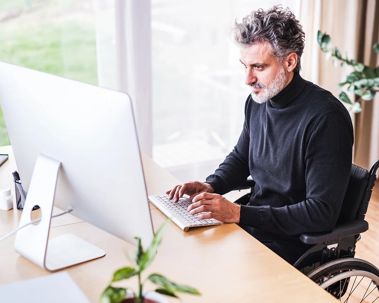 Man in rolstoel achter computer