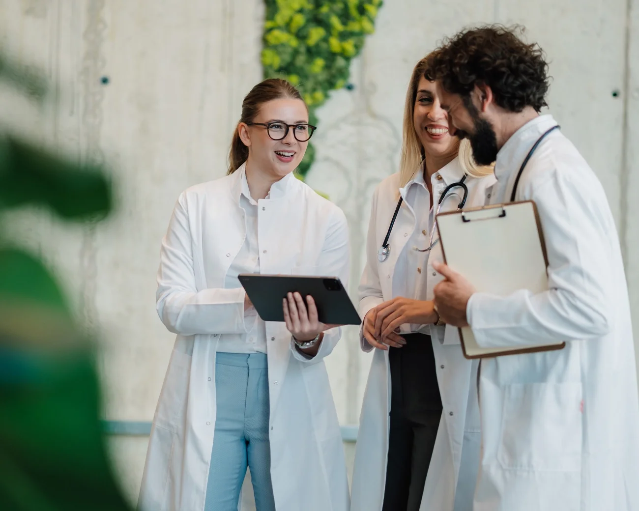 Drie zorgprofessionals in witte jassen met elkaar in gesprek