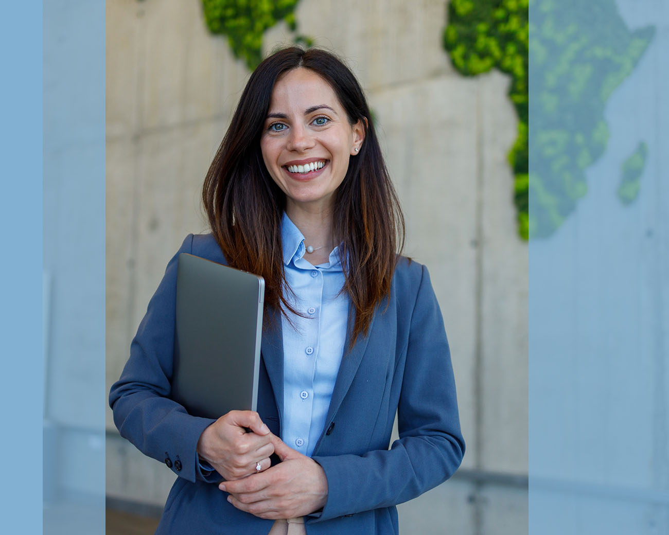 Co-manager staat met laptop voor kantoorpand