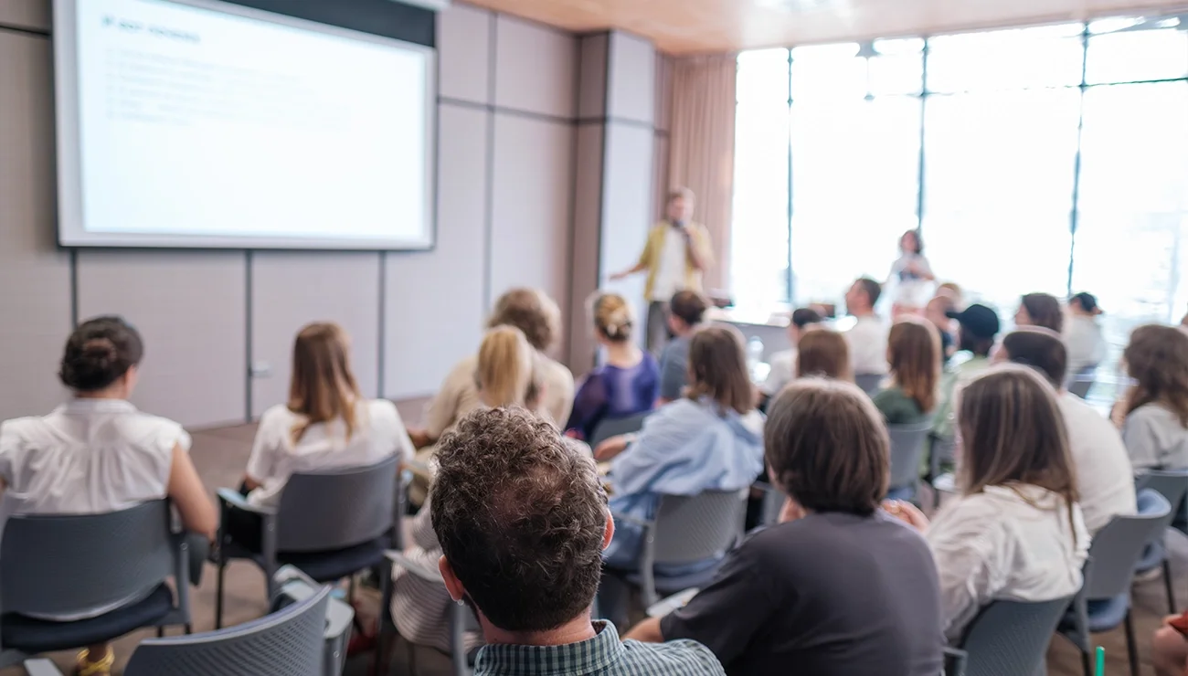 Spreker in zaal met groep mensen