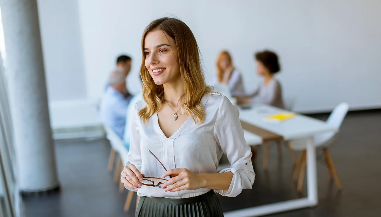 Vrouw die inspirerend naar buiten kijkt, achter haar een team die aan het werk is