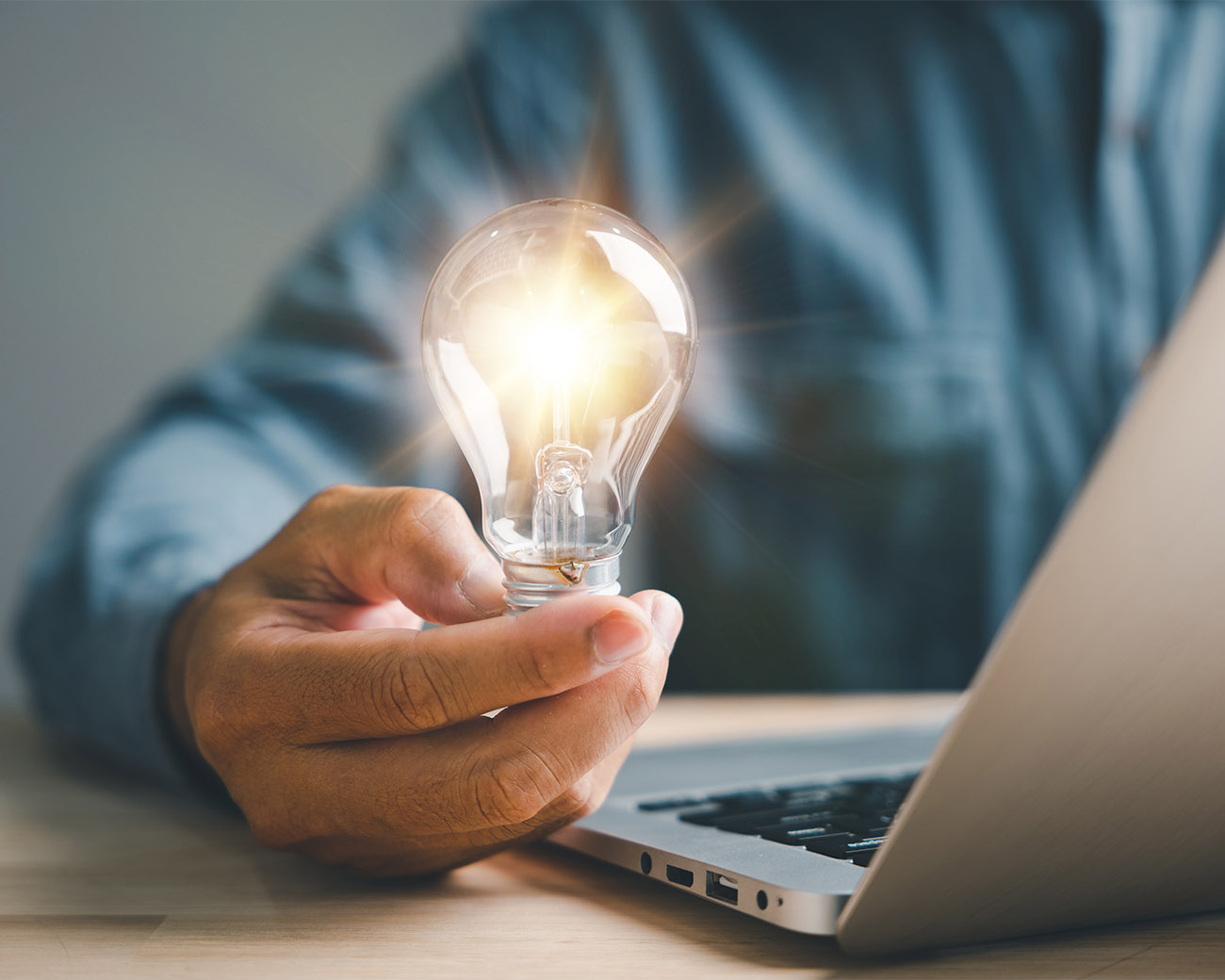 Persoon achter laptop houdt lamp vast