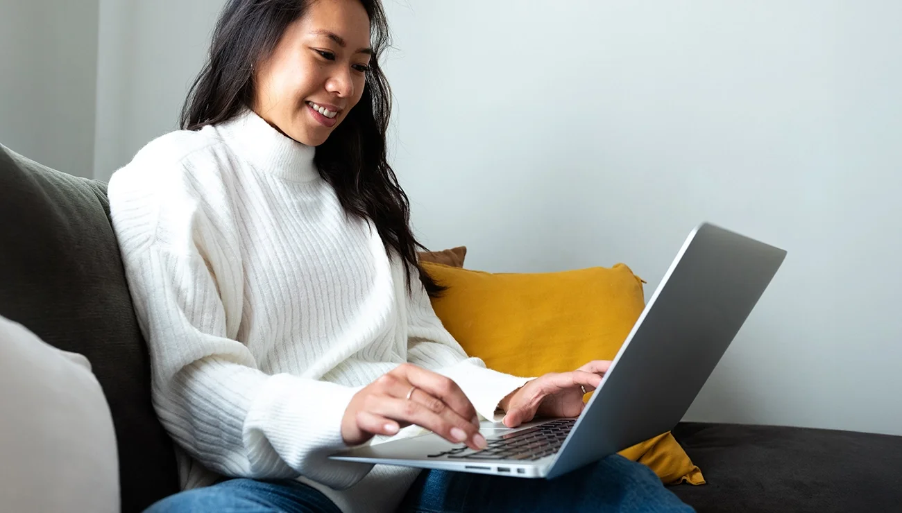 Meisje met witte trui met laptop op bank