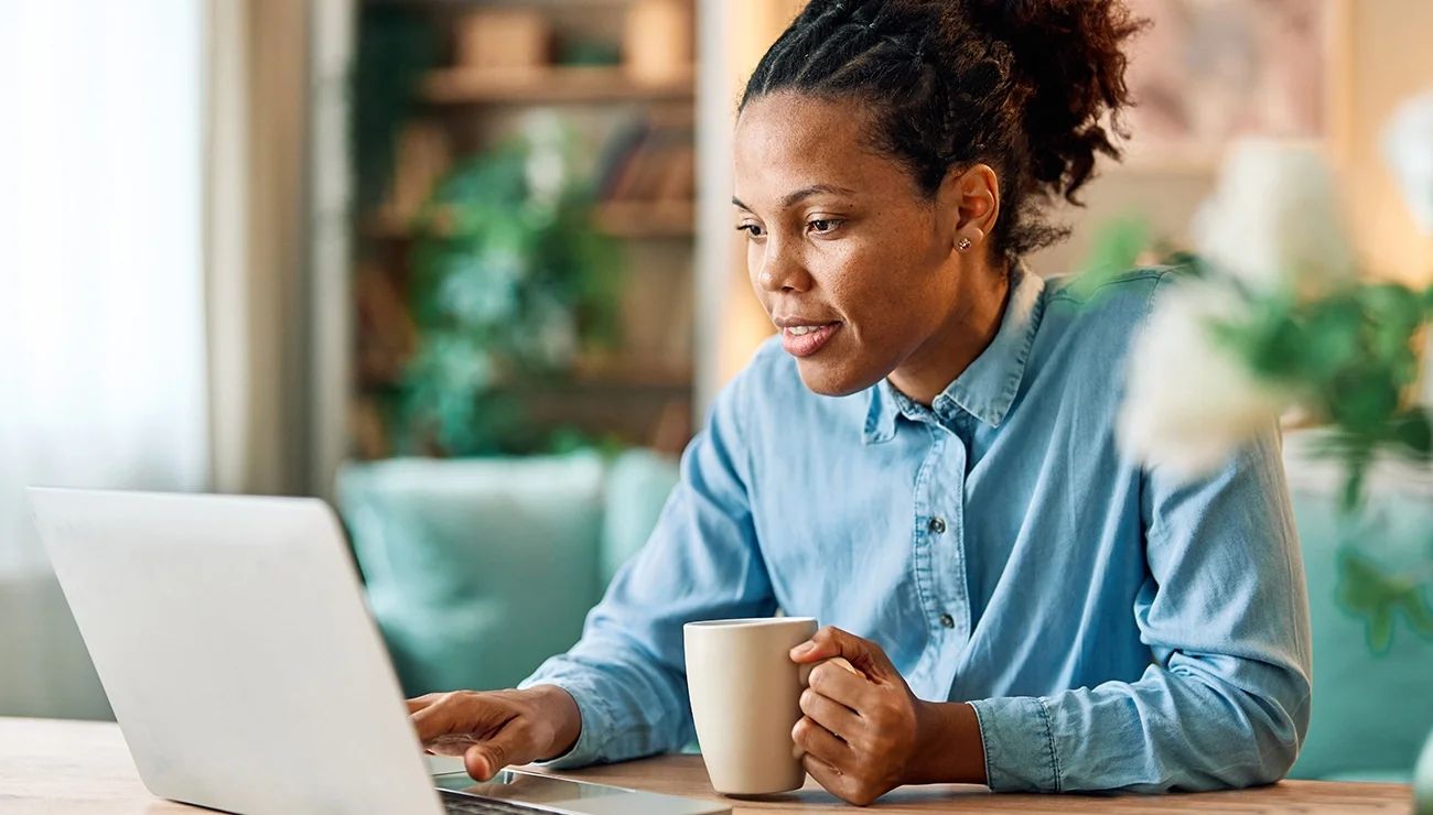 Vrouw achter laptop met koffiemok