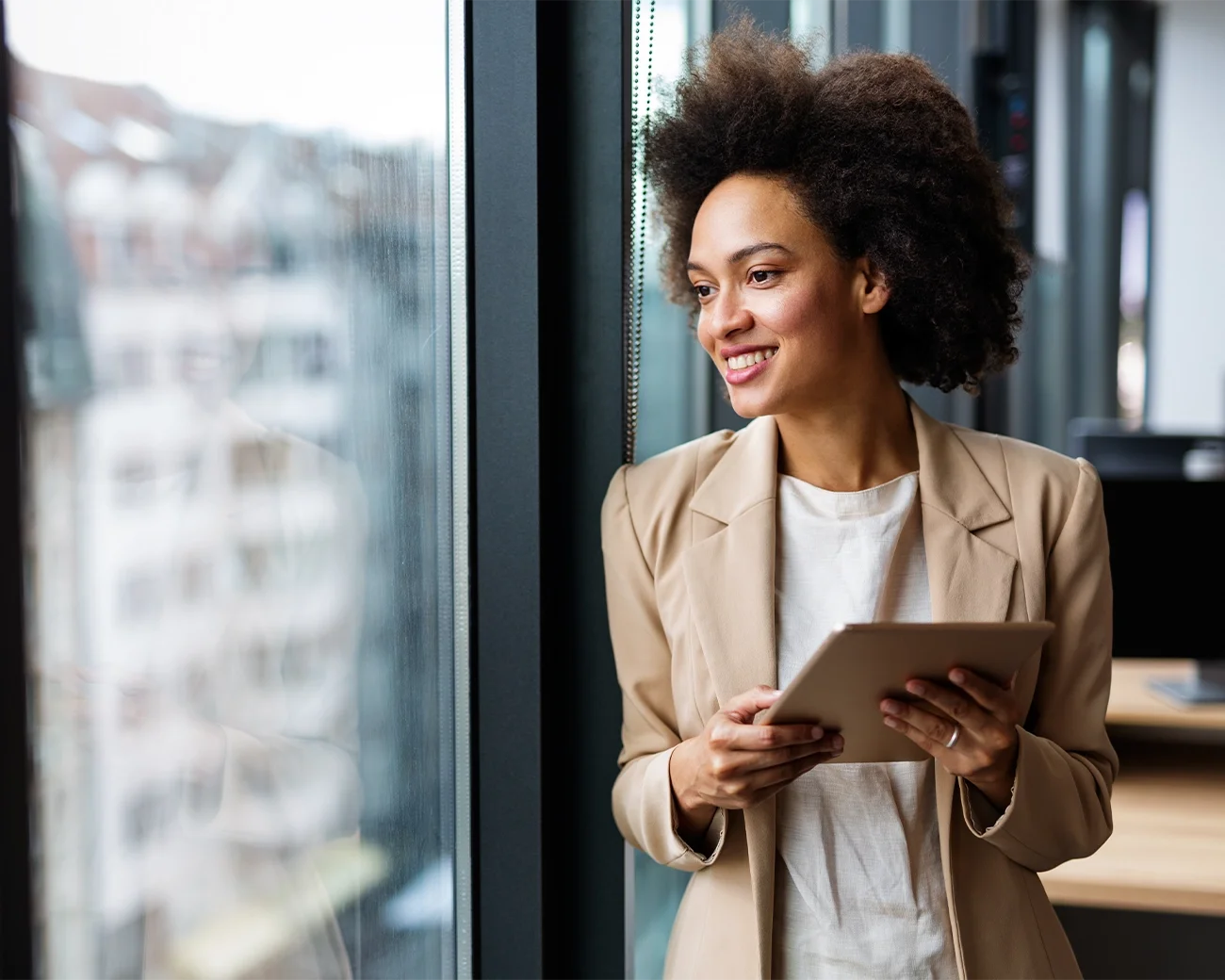 Vrouw met tablet in hand kijkt naar buiten