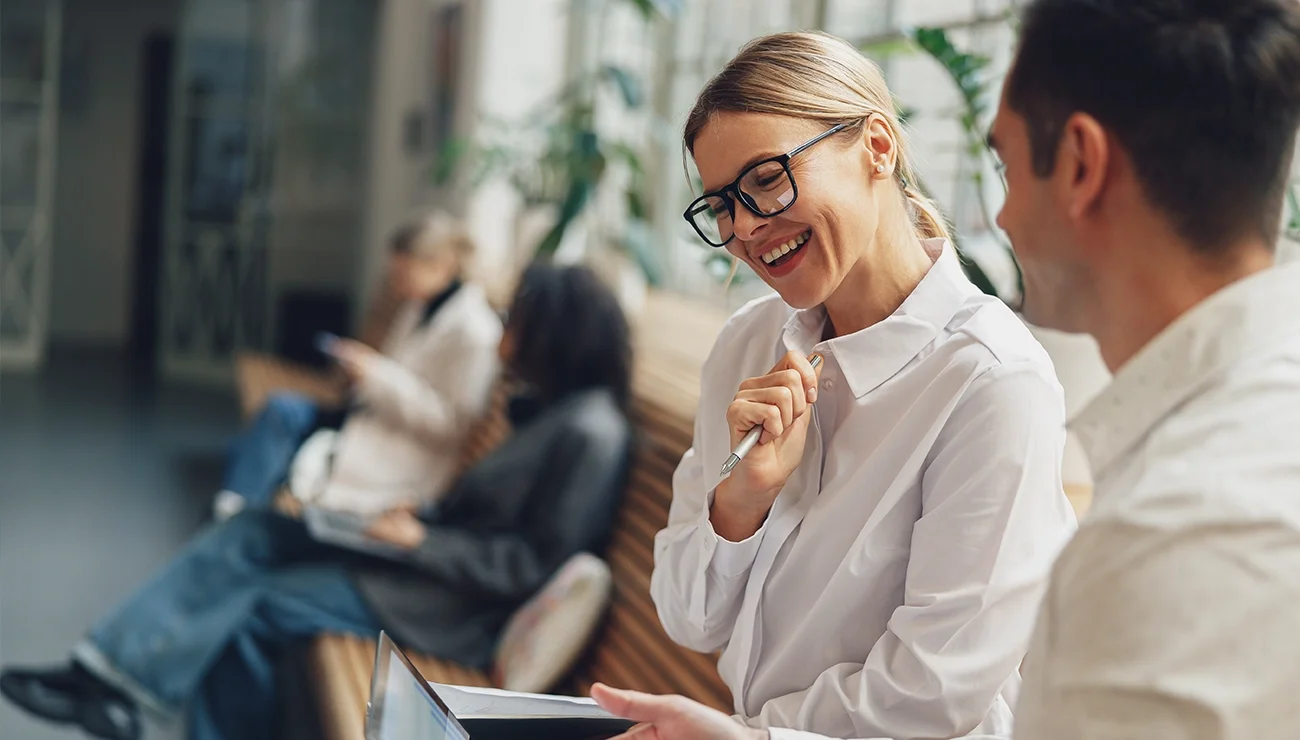 Twee collega’s zitten naast elkaar en bespreken iets wat zichtbaar is op een laptopscherm