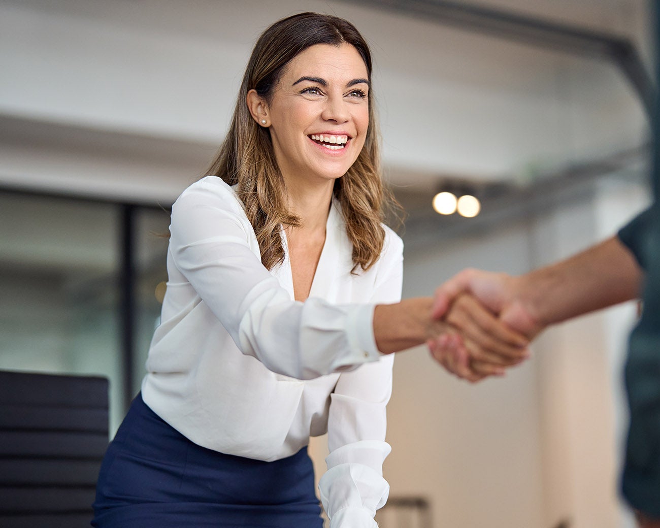 Lachende vrouw geeft persoon een hand