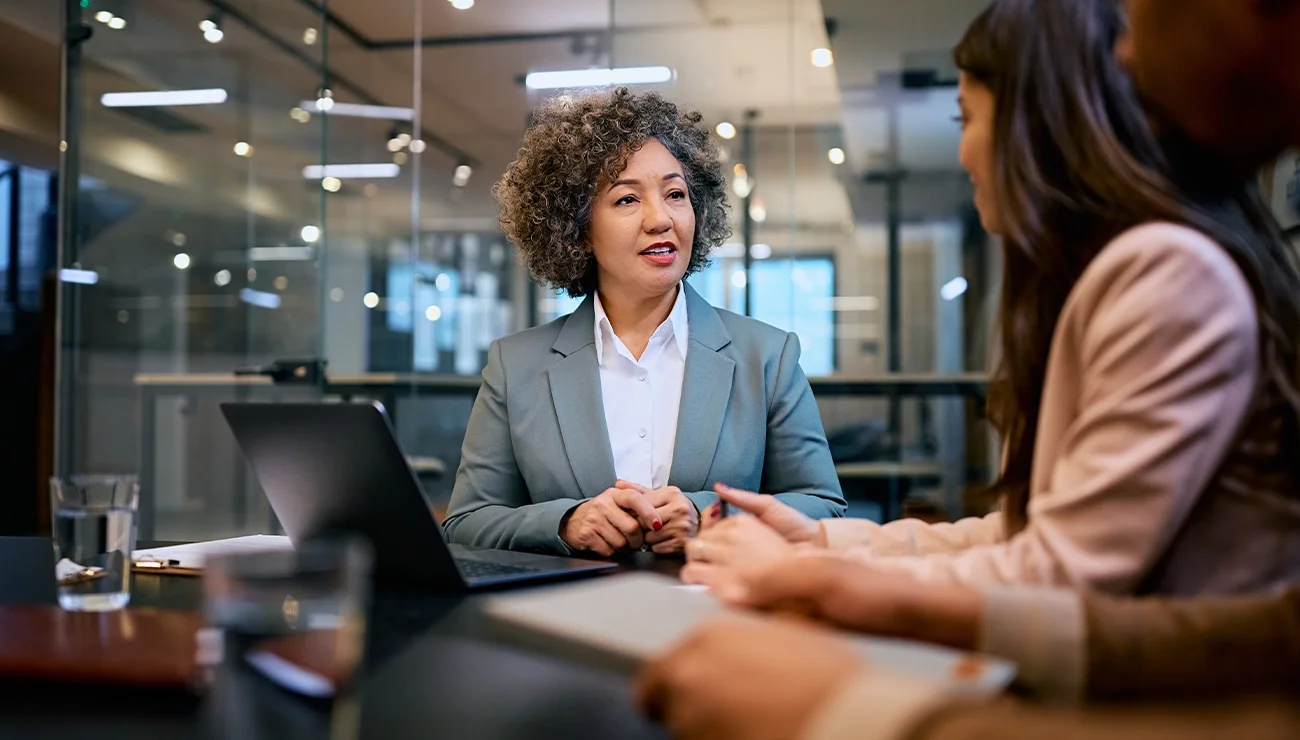 Vrouw overlegt met twee collega’s aan bureau