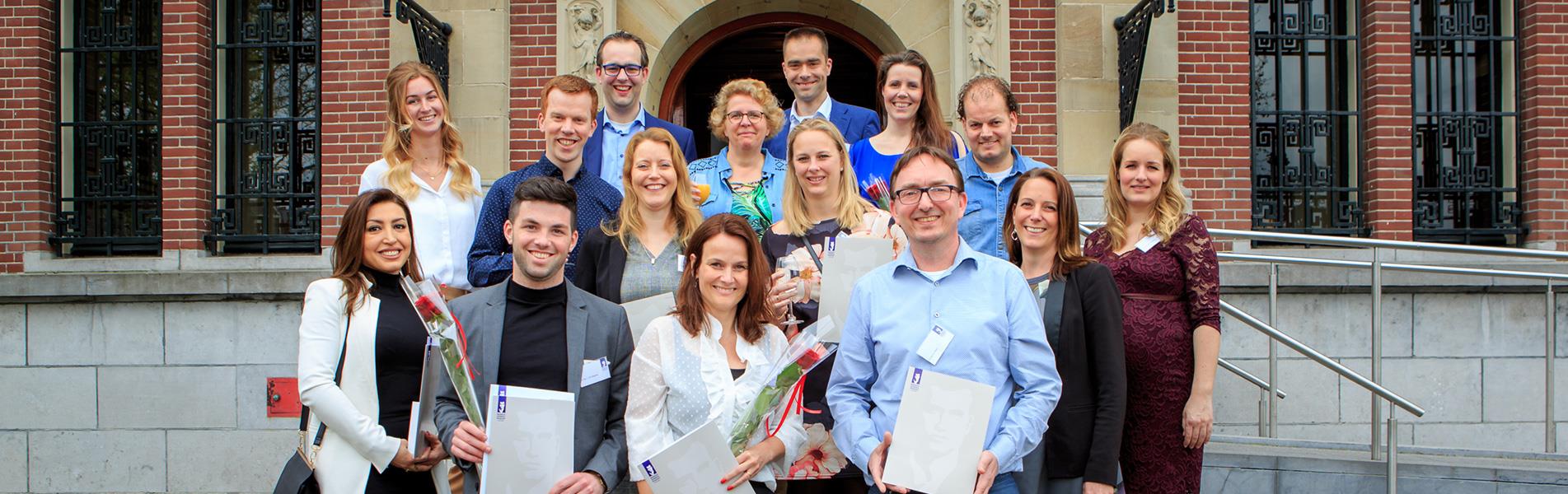 Groep MVP-studenten voor het Muntgebouw met MVP-diploma in hun hand