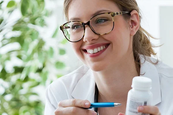 Zorgprofessional in witte blouse zit tegenover cliënt en lacht