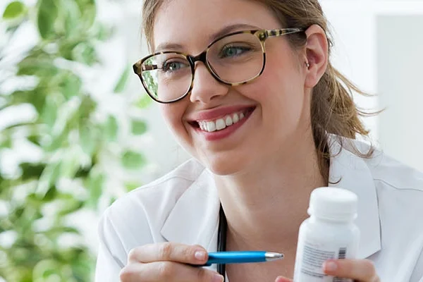 Zorgprofessional in witte blouse zit tegenover cliënt en lacht