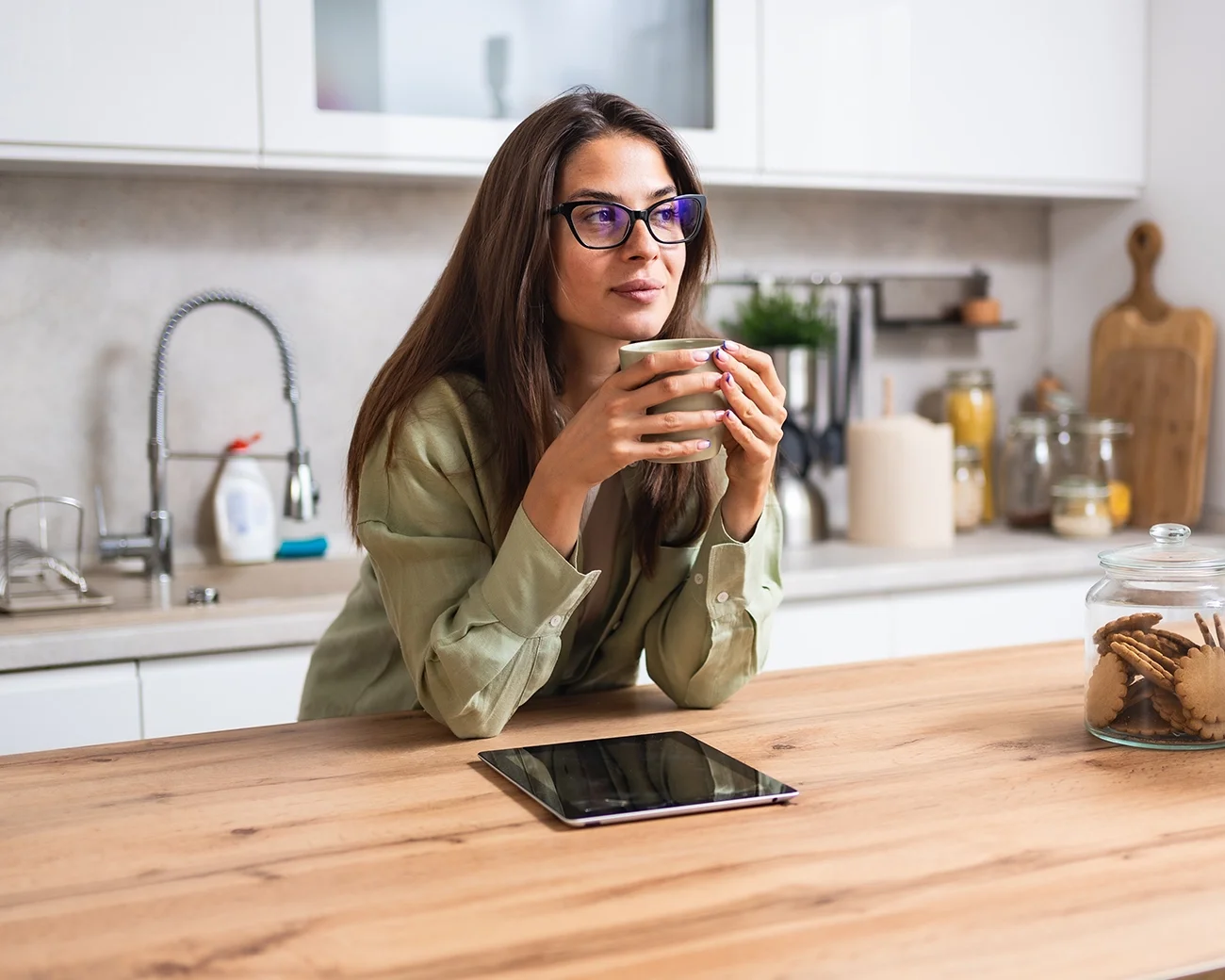 Vrouw kijkt voor zich uit met kop koffie in de hand