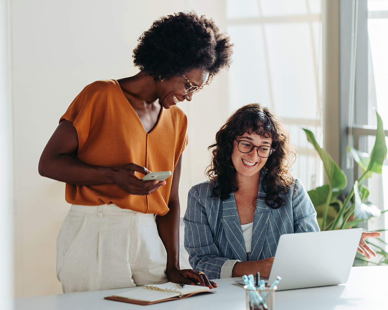 Twee vrouwen kijken lachend naar laptopscherm