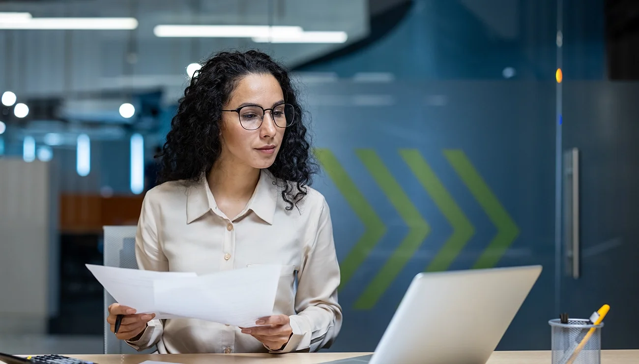 Vrouw zit aan een bureau en werkt op een laptop