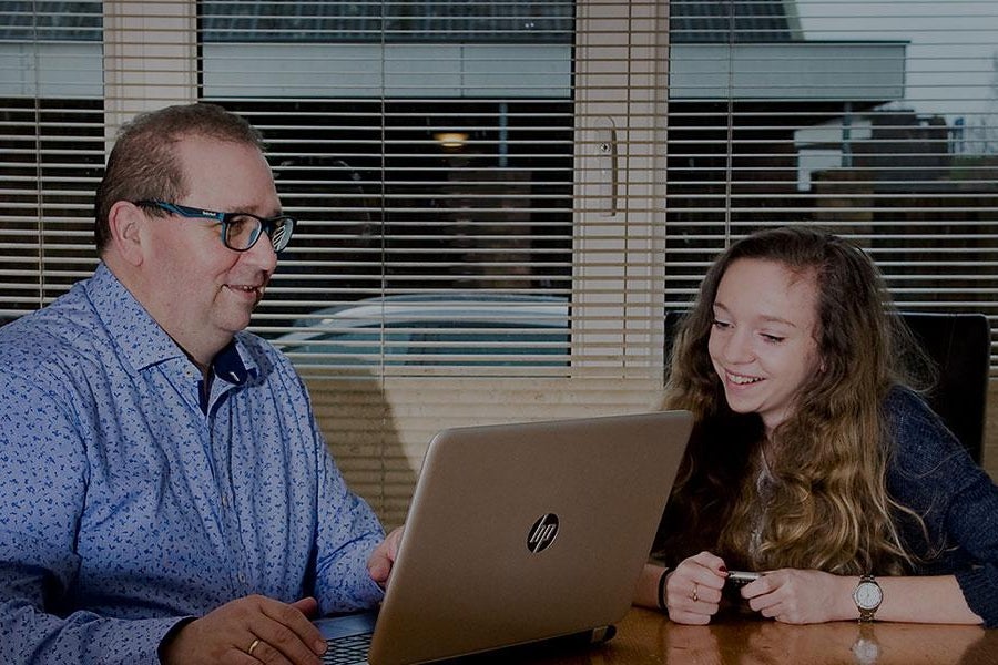 Man zit samen met zijn dochter achter een laptop