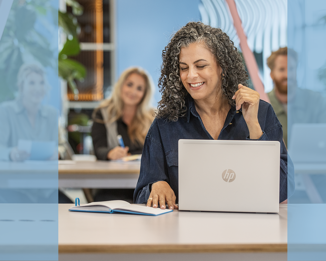 Lachende vrouw in klaslokaal met laptop en notitieblok.