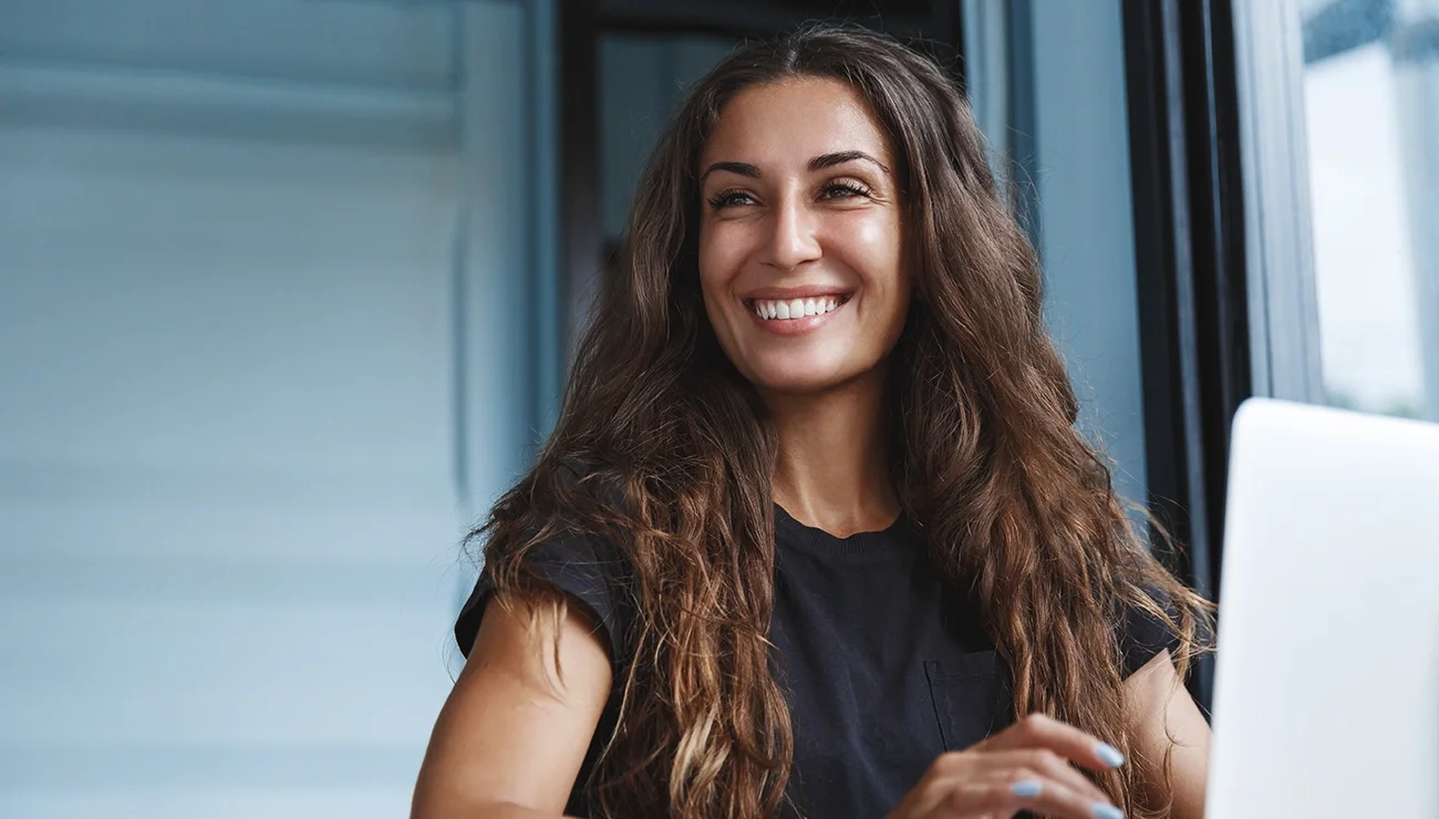 Vrolijke vrouw werkend achter een laptop